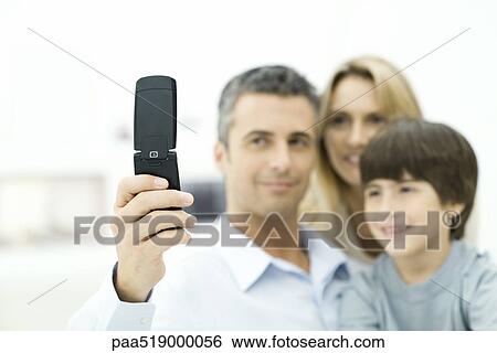 Family looking at cell phone together, focus on phone View Large Photo Image Stock Photograph - Family looking at cell phone together, focus on phone. Fotosearch
