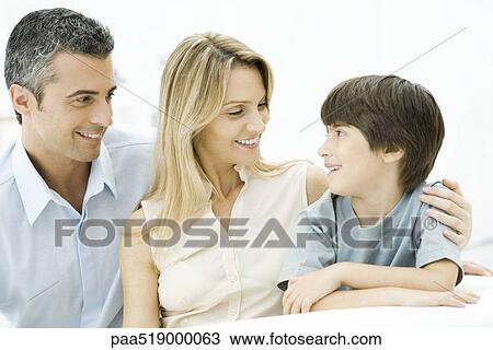 Family sitting together, smiling, mother's arm around son's shoulder View Large Photo Image Stock Image - Family sitting together, smiling, mother's arm around son's shoulder. Fotosearch