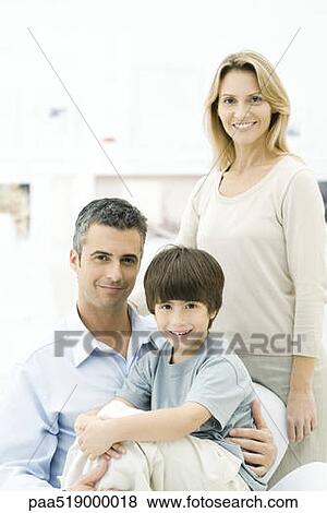 Stock Photo - Family smiling at camera, boy sitting on father's lap. Fotosearch