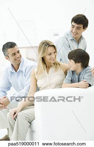 Family together on sofa, mother's arm around younger son's shoulder View Large Photo Image Stock Image - Family together on sofa, mother's arm around younger son's shoulder. Fotosearch