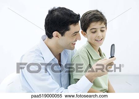 Father and son looking at cell phone together View Large Photo Image Stock Photography - Father and son looking at cell phone together. Fotosearch
