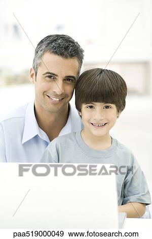 Father and son sitting with laptop computer, smiling, portrait View Large Photo Image Stock Photo - Father and son sitting with laptop computer, smiling, portrait. Fotosearch