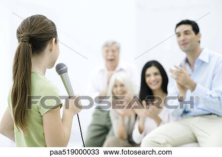 Girl holding microphone, family clapping in background View Large Photo Image Stock Image - Girl holding microphone, family clapping in background. Fotosearch