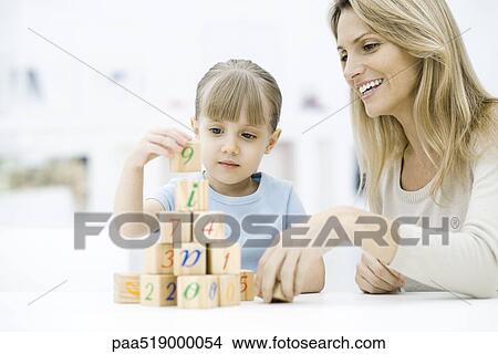 Little girl stacking blocks, mother watching and smiling View Large Photo Image Picture - Little girl stacking blocks, mother watching and smiling. Fotosearch