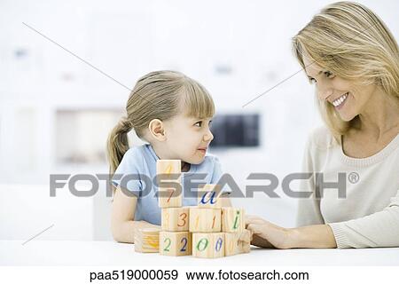 Mother and daughter sitting with blocks, smiling at each other View Large Photo Image Stock Photo - Mother and daughter sitting with blocks, smiling at each other. Fotosearch