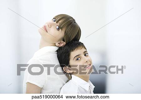 Picture - Mother and son leaning back to back, looking at camera, portrait. Fotosearch