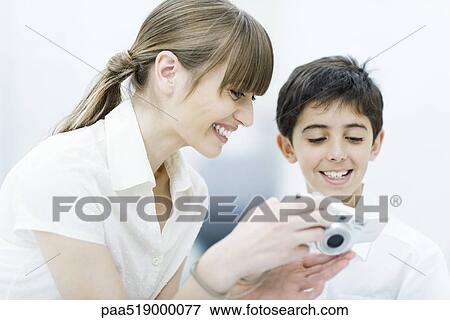 Mother and son looking at digital camera together, smiling View Large Photo Image Stock Photo - Mother and son looking at digital camera together, smiling. Fotosearch