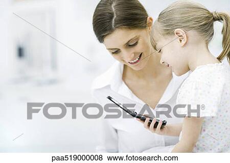 Mother and young daughter looking at cell phone together View Large Photo Image Stock Photo - Mother and young daughter looking at cell phone together. Fotosearch