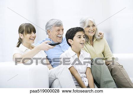 Multi-generation family sitting together on sofa, watching TV View Large Photo Image Stock Photo - Multi-generation family sitting together on sofa, watching TV. Fotosearch