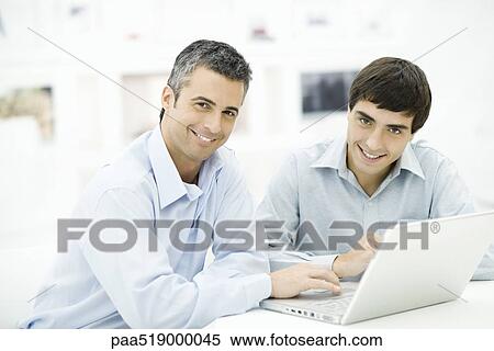 Two men using laptop computer together, both smiling at camera View Large Photo Image Stock Photography - Two men using laptop computer together, both smiling at camera. Fotosearch