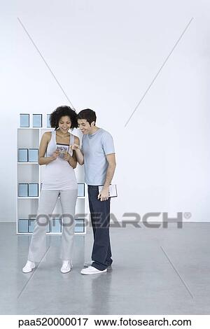 Stock Photo - Man and woman looking at DVD together, smiling. Fotosearch