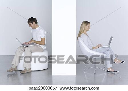 Man and woman sitting separately, using laptop computers, smiling View Large Photo Image Stock Photo - Man and woman sitting separately, using laptop computers, smiling. Fotosearch