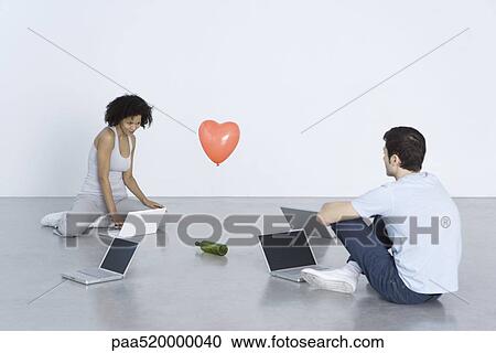 Man and woman sitting with laptop computers, playing "spin the bottle" View Large Photo Image Stock Image - Man and woman sitting with laptop computers, playing "spin the bottle". Fotosearch