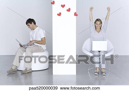 Man and woman using laptop computers, hearts floating between them, woman's arms raised View Large Photo Image Stock Photo - Man and woman using laptop computers, hearts floating between them, woman's arms raised. Fotosearch