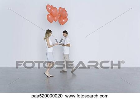 Man and woman walking toward each other with laptop computers and heart balloons, smiling View Large Photo Image Stock Image - Man and woman walking toward each other with laptop computers and heart balloons, smiling. Fotosearch