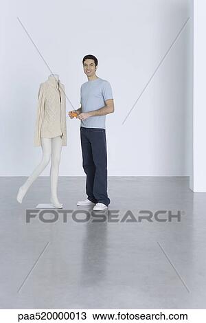 Man standing beside sweater on mannequin, holding price tag, smiling at camera View Large Photo Image Stock Image - Man standing beside sweater on mannequin, holding price tag, smiling at camera. Fotosearch