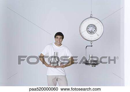 Man weighing cans on scale, smiling at camera View Large Photo Image Stock Image - Man weighing cans on scale, smiling at camera. Fotosearch