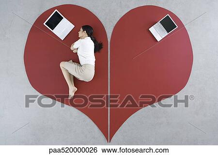 Woman lying on the ground with laptop on large broken heart, abandoned laptop behind her View Large Photo Image Stock Photograph - Woman lying on the ground with laptop on large broken heart, abandoned laptop behind her. Fotosearch