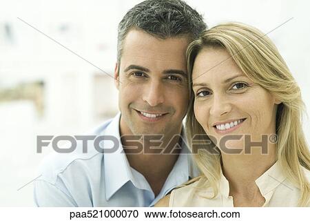 Stock Image - Couple smiling at camera, portrait. Fotosearch