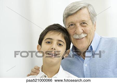 Stock Photograph - Grandfather and grandson smiling at camera, portrait. Fotosearch