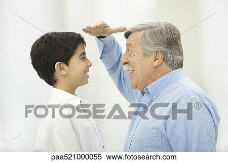 Grandfather comparing height with grandson, smiling at each other View Large Photo Image Stock Photography - Grandfather comparing height with grandson, smiling at each other. Fotosearch