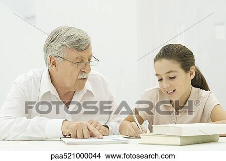 Picture - Grandfather helping granddaughter with homework. Fotosearch