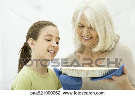 Grandmother and granddaughter looking down at freshly baked pie View Large Photo Image Stock Image - Grandmother and granddaughter looking down at freshly baked pie. Fotosearch