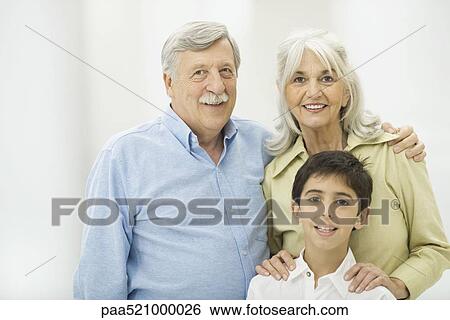 Stock Photograph - Grandparents and grandson smiling at camera, portrait. Fotosearch