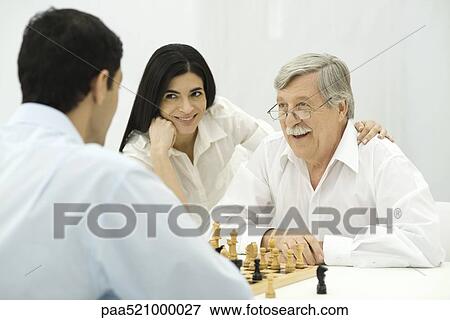 People playing chess, woman sitting with hand on senior man's shoulder View Large Photo Image Stock Photo - People playing chess, woman sitting with hand on senior man's shoulder. Fotosearch