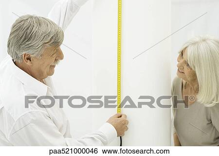Senior couple smiling at each other, man holding up measuring tape View Large Photo Image Stock Photograph - Senior couple smiling at each other, man holding up measuring tape. Fotosearch
