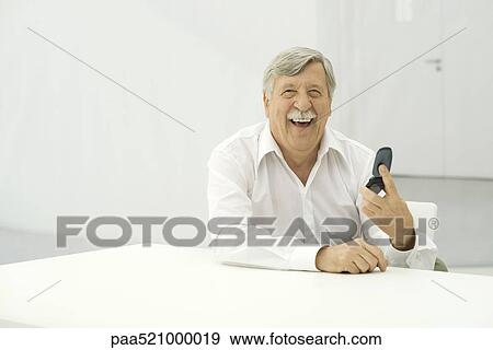Senior man laughing, holding cell phone, looking at camera View Large Photo Image Stock Photo - Senior man laughing, holding cell phone, looking at camera. Fotosearch