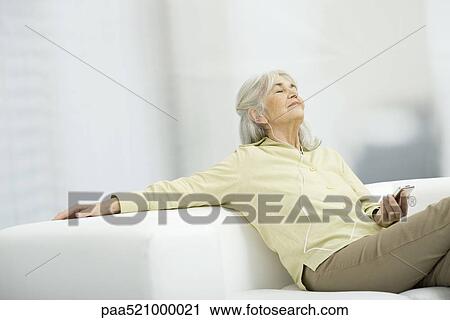 Senior woman listening to music, sitting on couch with eyes closed View Large Photo Image Stock Image - Senior woman listening to music, sitting on couch with eyes closed. Fotosearch