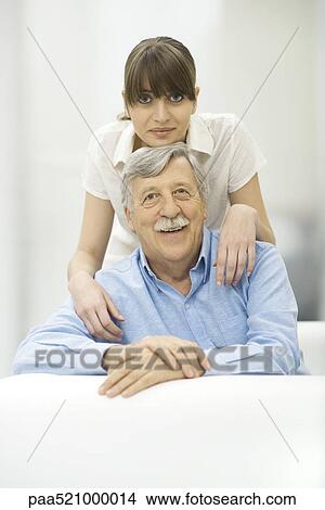Picture - Woman resting chin on top of father's head, both smiling at camera, portrait. Fotosearch