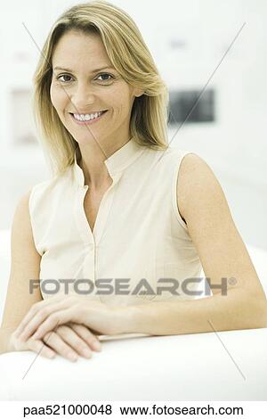 Stock Photo - Woman smiling at camera, hands folded, portrait. Fotosearch