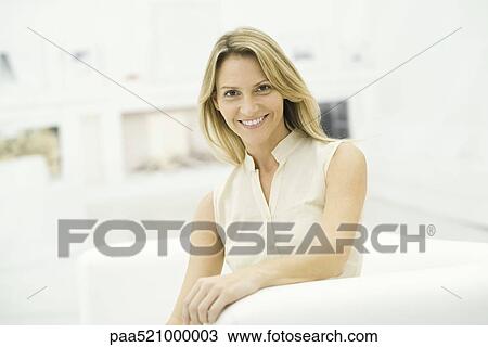 Woman smiling at camera, sitting in armchair, portrait View Large Photo Image Stock Image - Woman smiling at camera, sitting in armchair, portrait. Fotosearch