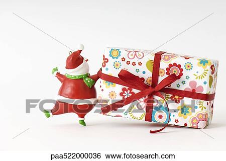 Stock Photograph - Santa Claus figurine pulling Christmas present. Fotosearch