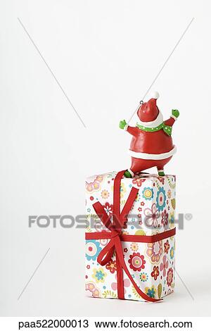Stock Image - Santa Claus figurine standing on top of Christmas present. Fotosearch