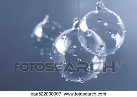 Three glass Christmas tree ornaments suspended against blue background View Large Photo Image Stock Photo - Three glass Christmas tree ornaments suspended against blue background. Fotosearch
