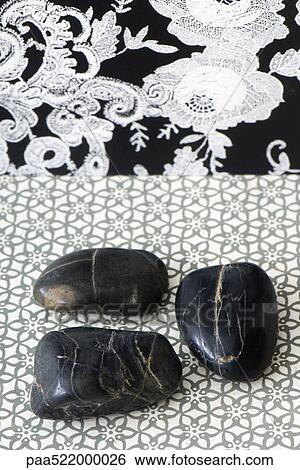 Three polished pebbles arranged against patterned background View Large Photo Image Stock Photograph - Three polished pebbles arranged against patterned background. Fotosearch