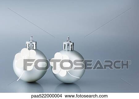 Two silver Christmas tree ornaments decorated with white flowers View Large Photo Image Picture - Two silver Christmas tree ornaments decorated with white flowers. Fotosearch