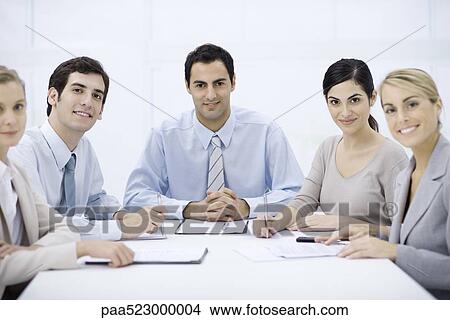Picture - Businessman sitting with colleagues at conference table. Fotosearch