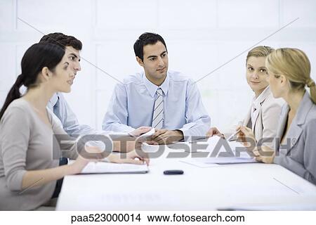 Picture - Businessman sitting with colleagues at conference table. Fotosearch