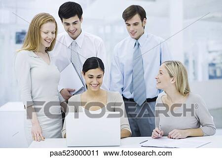 Stock Image - Group of professionals gathered around laptop computer, smiling. Fotosearch