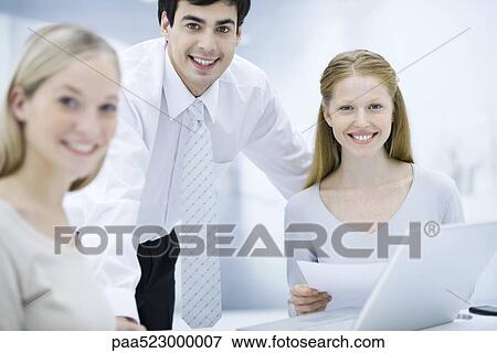 Office workers smiling at camera, one woman holding document View Large Photo Image Stock Photo - Office workers smiling at camera, one woman holding document. Fotosearch