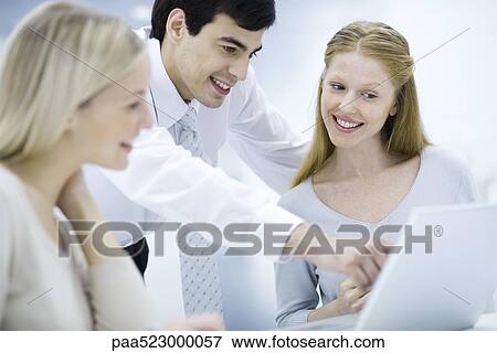 Professional man looking over female colleague's shoulder, pointing at laptop computer View Large Photo Image Stock Photo - Professional man looking over female colleague's shoulder, pointing at laptop computer. Fotosearch