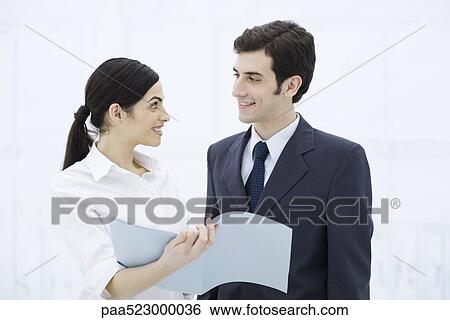 Professional woman showing male colleague document, both smiling View Large Photo Image Stock Photograph - Professional woman showing male colleague document, both smiling. Fotosearch