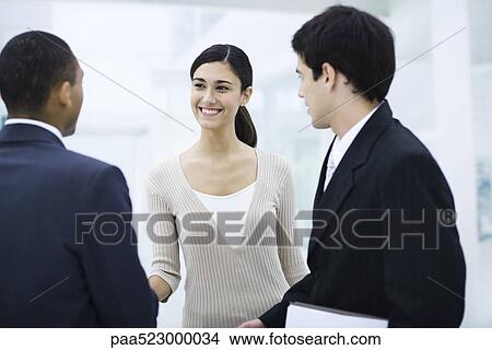 Professional woman standing with two businessman, shaking one man's hand, smiling View Large Photo Image Picture - Professional woman standing with two businessman, shaking one man's hand, smiling. Fotosearch