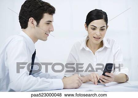 Professionals looking at cell phone together, smiling View Large Photo Image Stock Photo - Professionals looking at cell phone together, smiling. Fotosearch