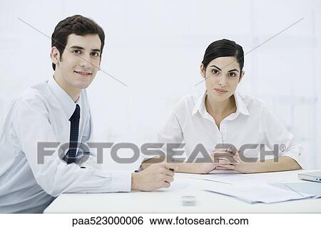 Professionals sitting with documents, smiling at camera View Large Photo Image Stock Photograph - Professionals sitting with documents, smiling at camera. Fotosearch