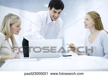 Stock Image - Professionals working with laptop computer together. Fotosearch